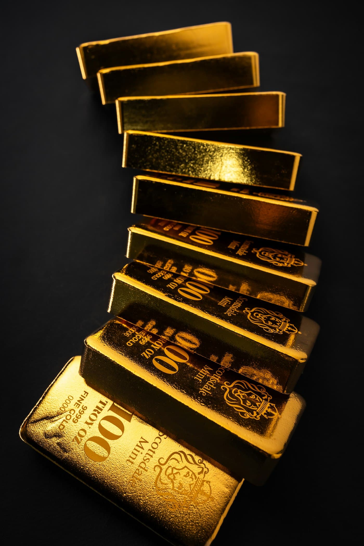 A cascading stack of 100-ounce gold bars against black